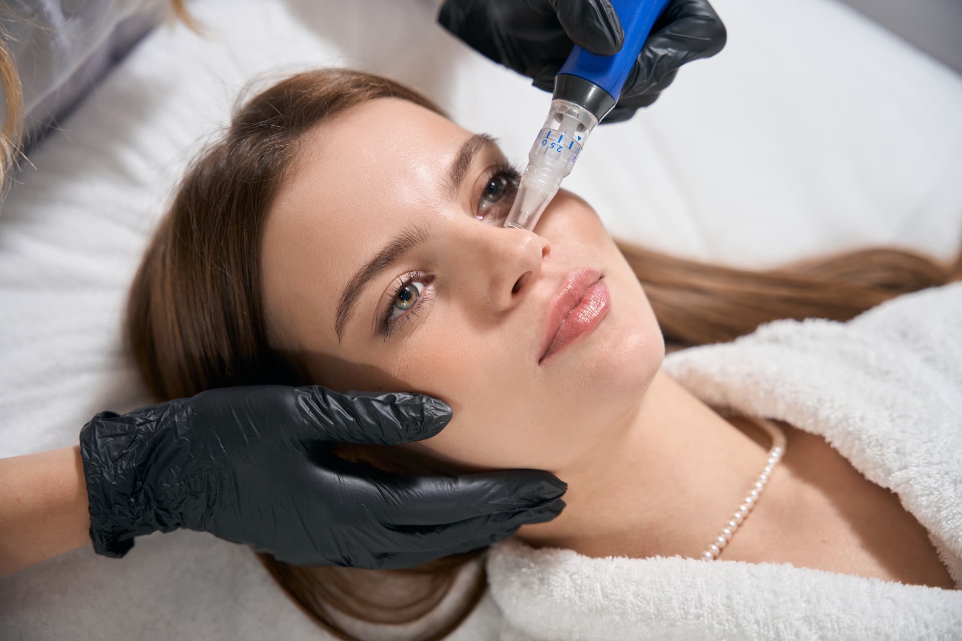 Microneedling-Gerät in Anwendung an der Wange einer Patientin in der Ordination